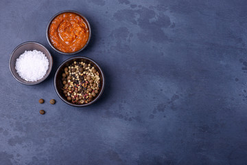 Sauce with salt and pepper on dark background