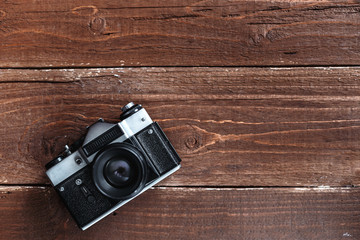 Retro photo camera is lying on a wooden background with a lot of free space on it