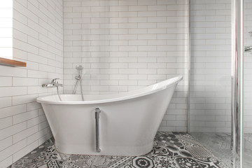 Naklejka na ściany i meble White bathroom on a tiled wall background Classic bathtub