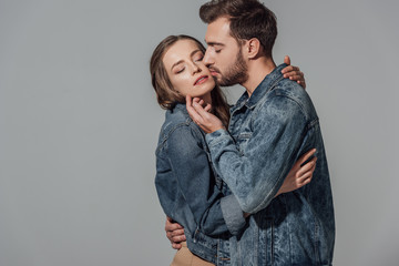 seductive young couple with closed eyes embracing and touching each other isolated on grey
