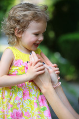 Happy girl hold female hands in summer park outdoor