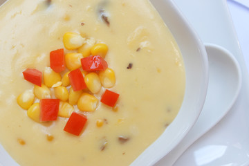 Corn soup and tomato in white bowl on white dish .closeup