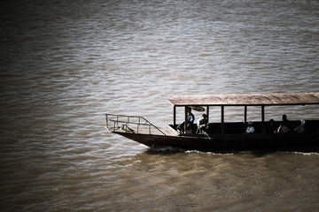 Fototapeta na wymiar Boat sailing on the river with backdrop of shining sun