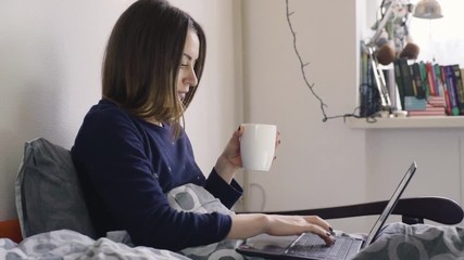 Young woman on her bed with laptop at home