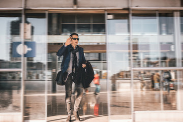 Businessman with hand raised getting out of railway station and greeting someone.