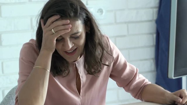 Tired businesswoman with computer falling asleep on table in office
