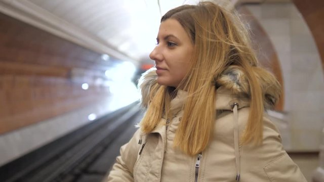 Attractive woman standing in metro and using the smartphone, waiting a train.