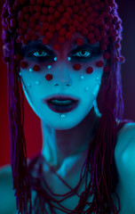 Portrait of woman with fantasy make up and sequins against red background