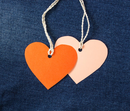 The tags in the form of red and pink heart on denim background. Background Valentine's Day.