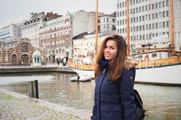 Brunette girl in a winter jacket against the port with yachts