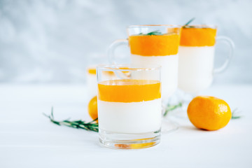 Tangerine panna cotta dessert with rosemary in wineglasses