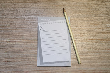 A memo pad and yellow pencil on wood office table.