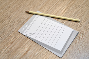 A memo pad and yellow pencil on wood office table.