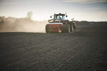 Red tractor with sowing machine on a ploughed field