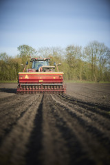 Red tractor with sowing machine on a ploughed field