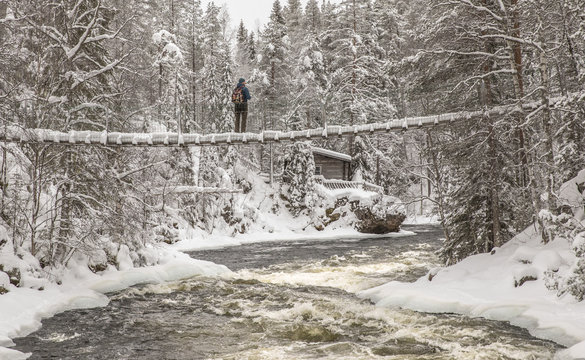 hiker on a bridge over fast moving river in Finnish Lapland