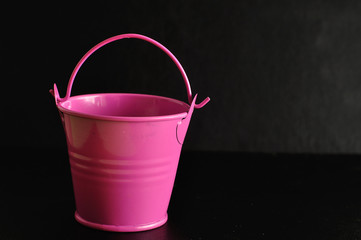 A pink miniature bucket isolated on a black background