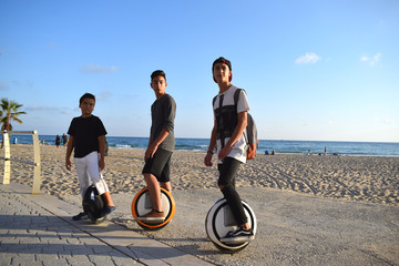 Three boys with MonoWheel after riding on a beach promenade © Olga