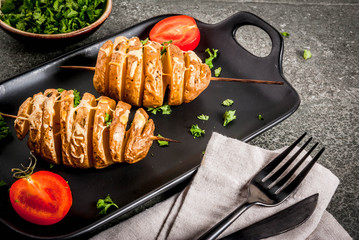 Tornado Cheesy Potatoes with Parsley and Tomatoes, on black stone background, copy space