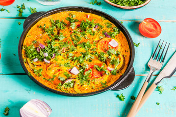 Indian food recipes, Indian Masala Egg Omelet, with fresh vegetables - tomato, hot chili pepper, parsley, light blue wooden background, copy space