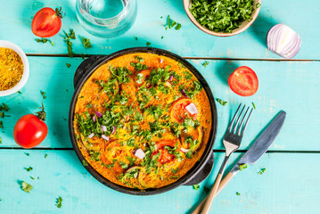 Indian food recipes, Indian Masala Egg Omelet, with fresh vegetables - tomato, hot chili pepper, parsley, light blue wooden background, copy space top view