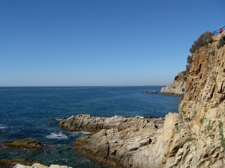 Bird's eye view steep rocky cliff into the sea during summer season