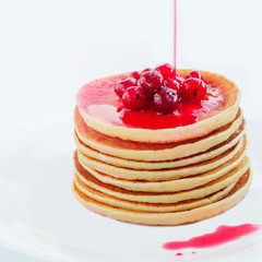 Pancakes with berry syrup on a plate on a white background