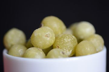 Frozen gooseberries on a dark background close up