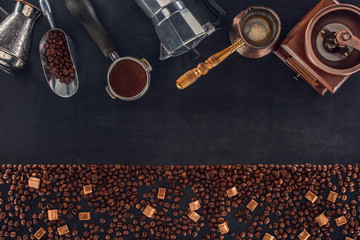 top view of roasted coffee beans with brown sugar and various coffee makers and grinders on black