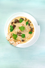Tom Yam, traditional Thai soup with shrimps and mushrooms, on teal
