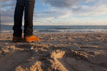 Close-up of legs - Girl looking the sea on the beach at sunset - winter season - story telling...