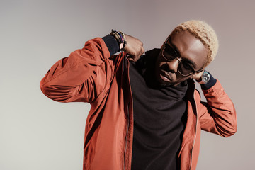 Stylish young african american man straightens his jacket isolated on light background