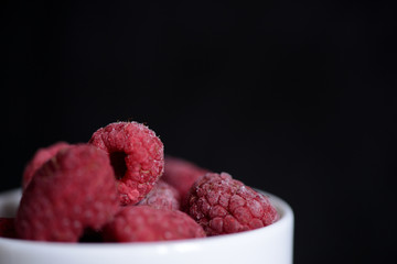 Frozen berries of raspberries on a dark background close up