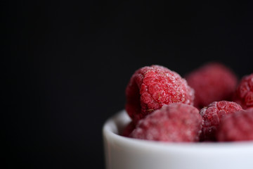 Frozen berries of raspberries on a dark background close up