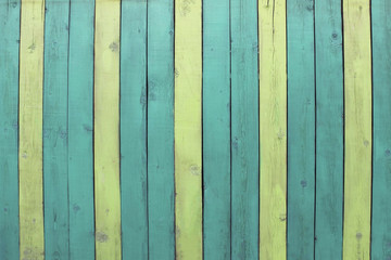 Old wooden fence boards are painted yellow and green background