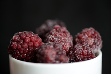 Blackberry berries covered with hoarfrost on a dark background close up