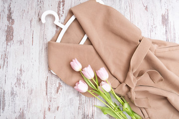 Beige coat with a belt, pink tulips, white trempel. Fashionable concept.