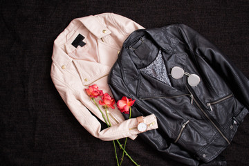 Fashionable concept. Two leather jackets on a black background and roses. Top view