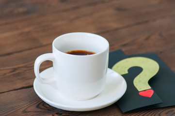 A cup of black coffee and card on a wooden backdrop. Valentine's Day background. Copy space.