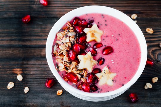 pink smoothie bowl with pomegranate, homemade granola, banana stars and chia seeds