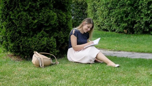 Young woman sitting in park with a diary