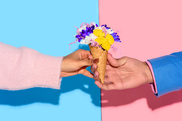 Cropped image of hands with flowers on pink and blue background