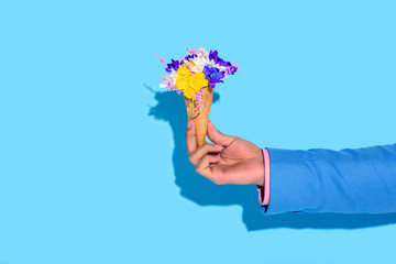 Cropped image of man hand holding flowers on blue background