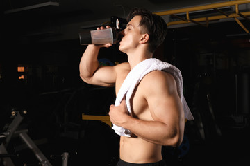 Fototapeta na wymiar Strong man drinking water in gym