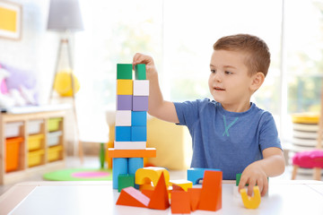 Cute little boy playing with blocks at home