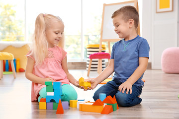 Cute little children playing with blocks at home