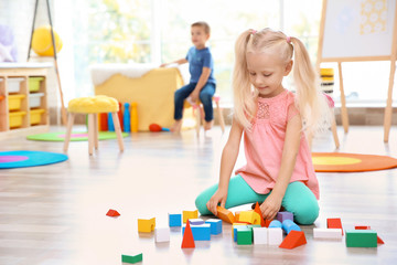 Cute little girl playing with blocks at home