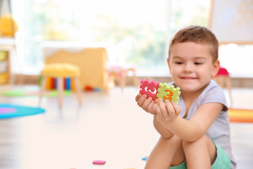Cute little boy playing with math puzzle at home