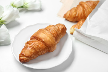 Plate with delicious croissant on white background