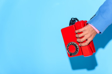 Cropped image of man in jacket with retro phone in hand, on blue background